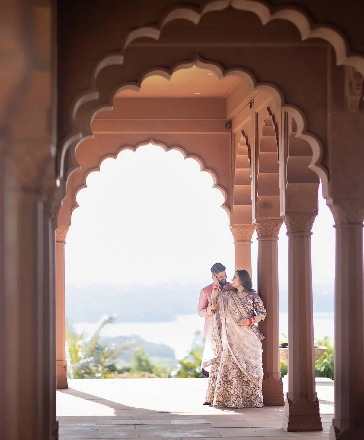 A couple embracing beneath the palace's scalloped archways overlooking the coast