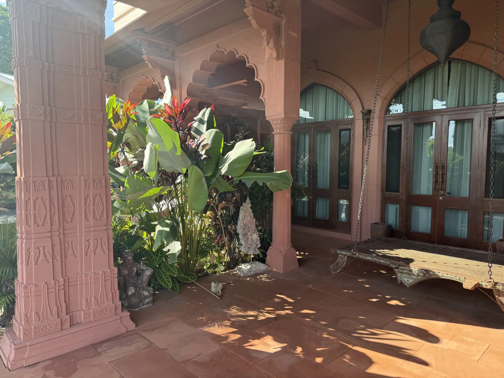 The gardens at Jodha Bai, a hanging daybed on the veranda among banana palms and cordyline