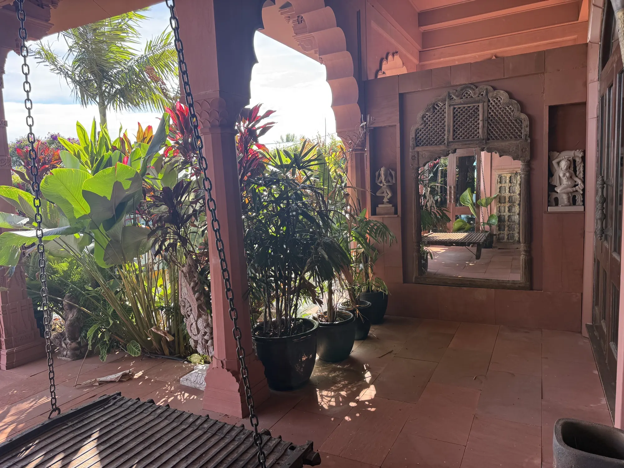 The gardens at Jodha Bai, the veranda swing seat beside potted palms and carved stone niches