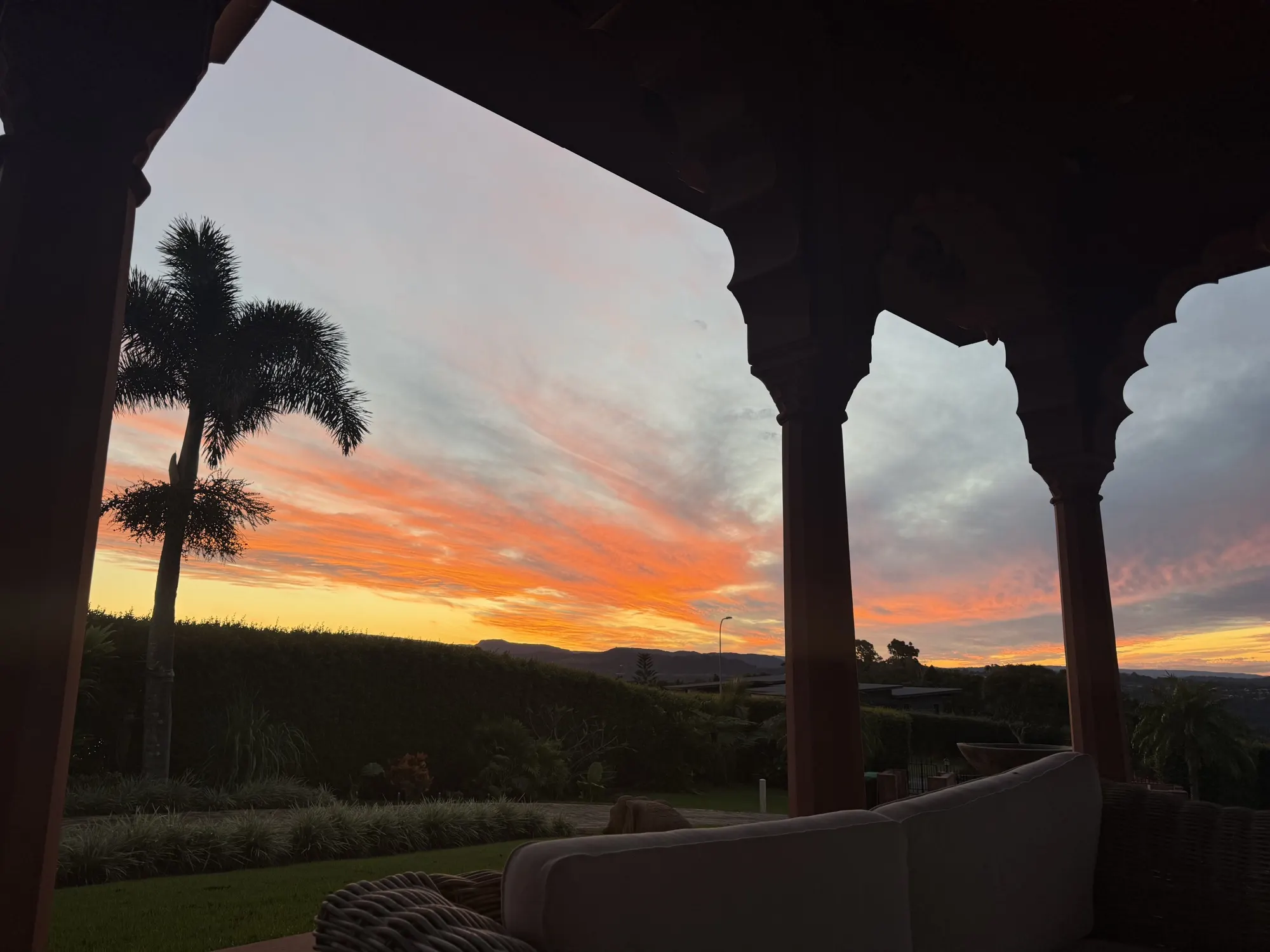 The gardens at Jodha Bai, a sunset silhouette of palm trees beyond the veranda archways
