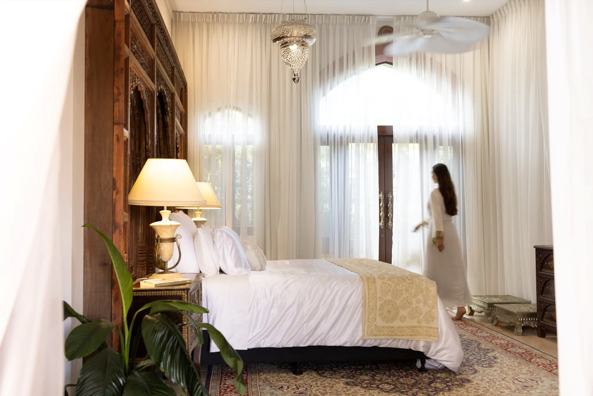 The Jodha Bai Suite, a carved wood screen headboard beneath a silver pendant lantern