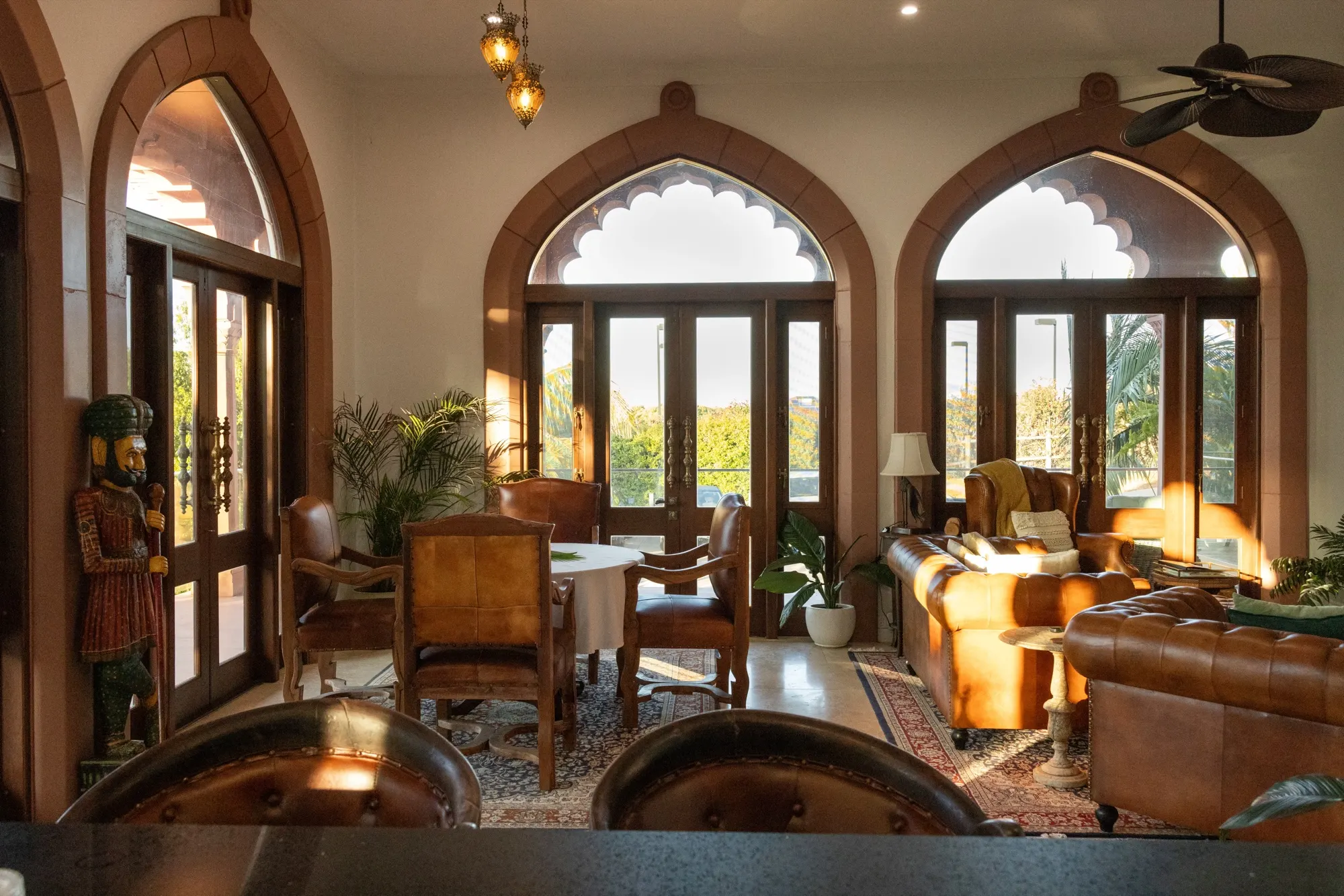 The Jodha Bai Suite, the dining table and leather chesterfield beneath twin arched doors