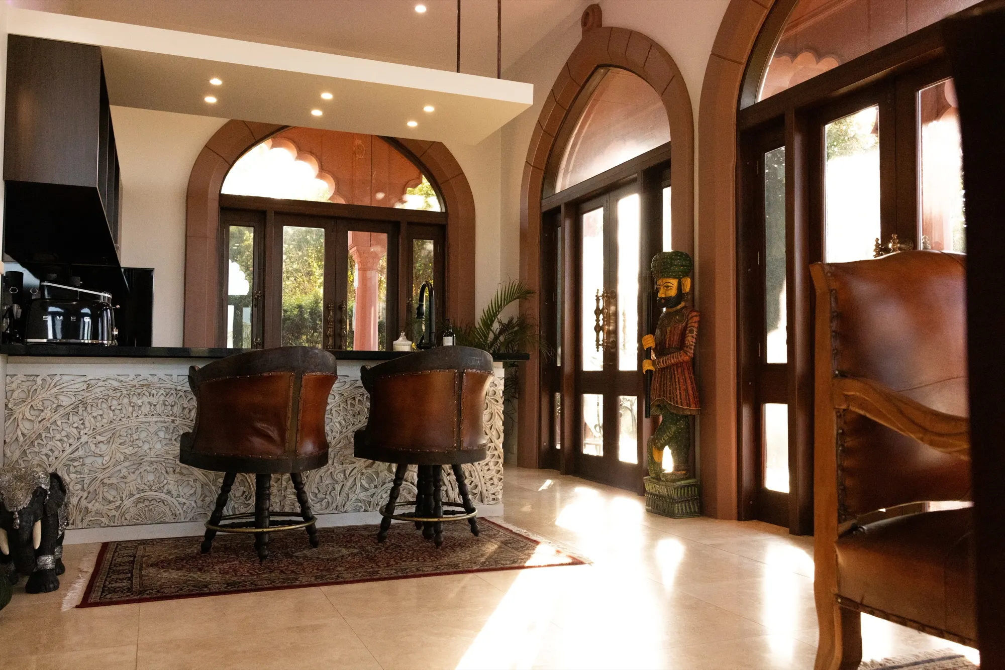 The Jodha Bai Suite, leather barstools at the kitchen counter beside a carved stone frieze