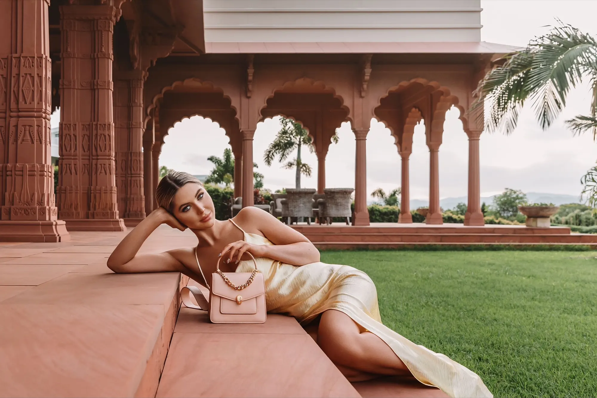 A model reclining on the verandah steps beneath the palace's scalloped archways