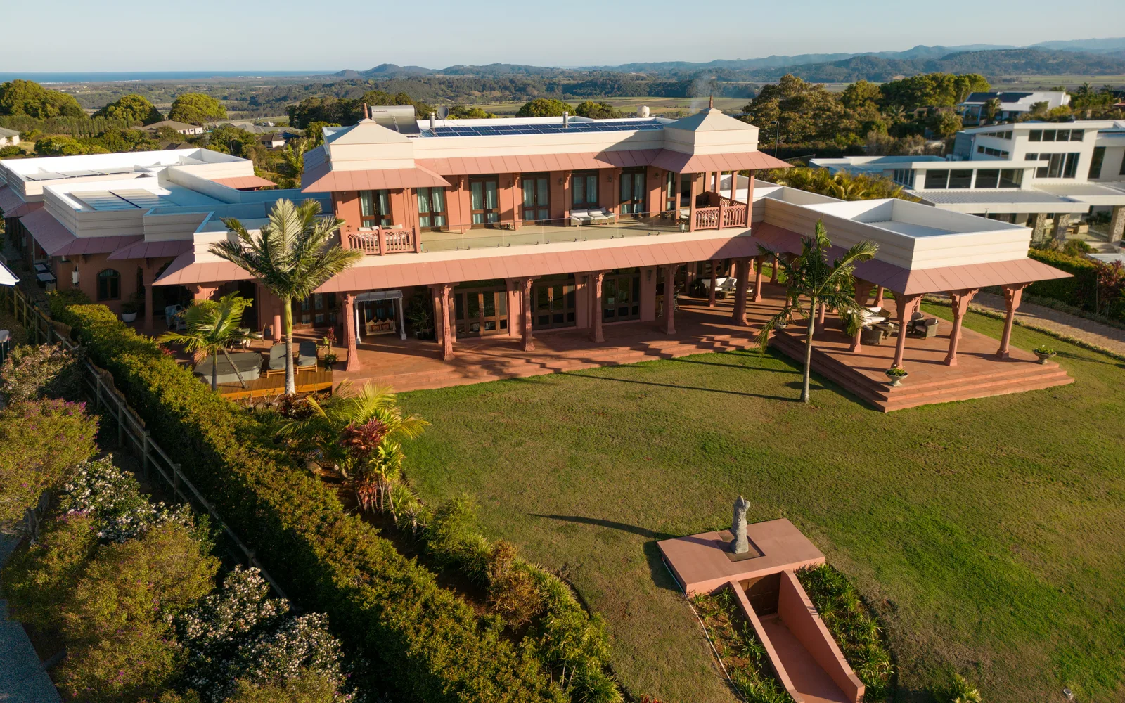 Aerial view of Jodha Bai Estate's rear terrace and lawn, with the coastline in the distance