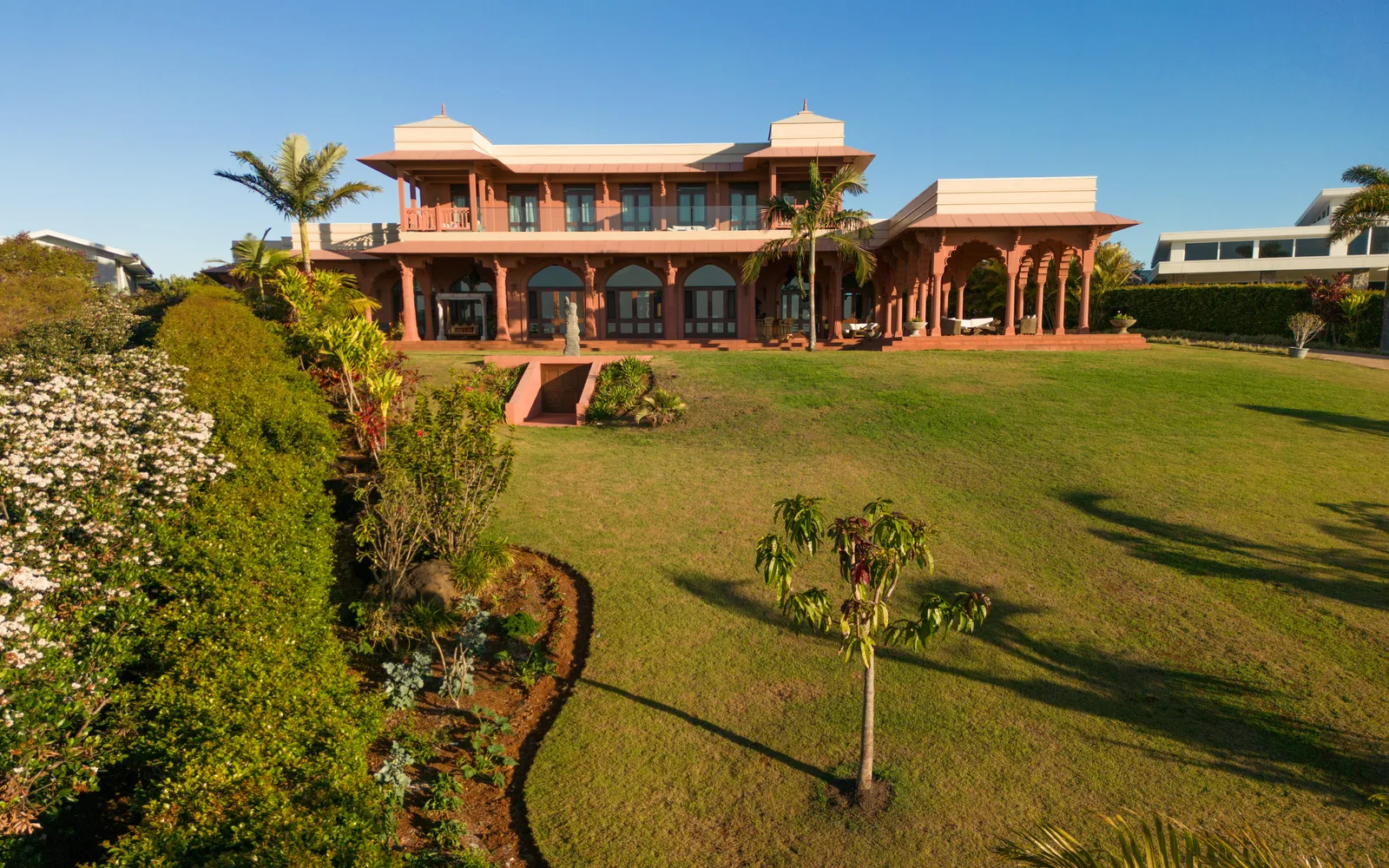 Jodha Bai Estate's rear facade and lawn bordered by flowering hedges